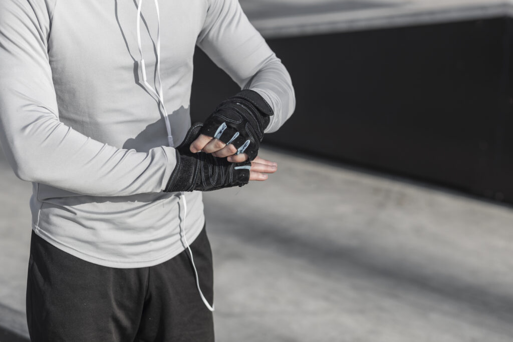 Male parkour enthusiast getting ready for practice by wearing parkour gloves.