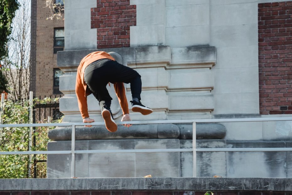 A traceur gripping a rail while vaulting over an obstacle.