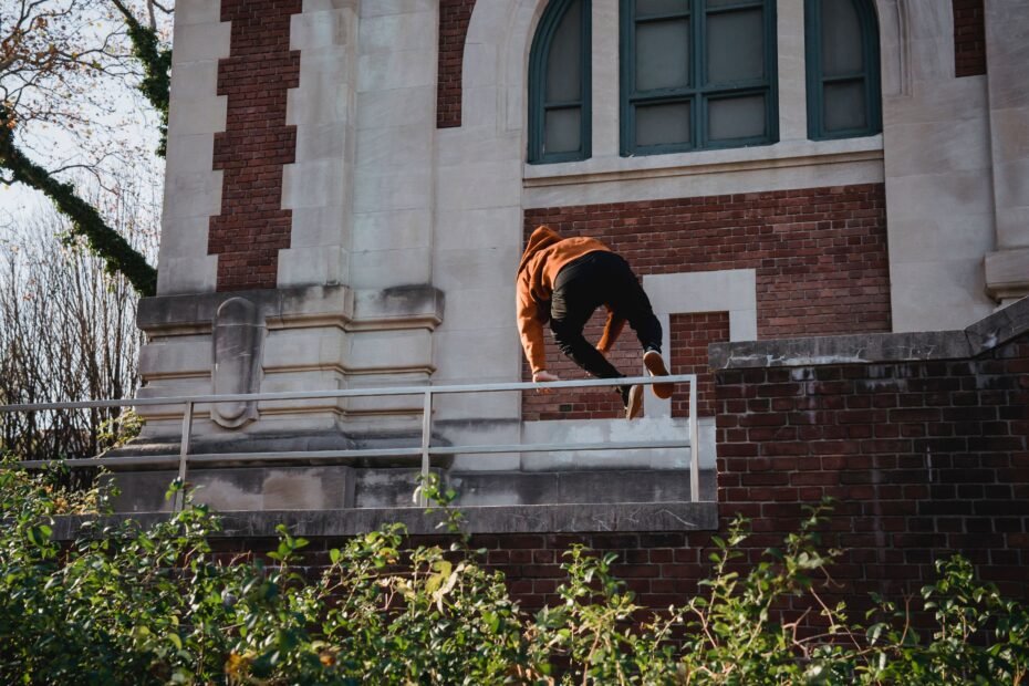 A traceur jumping over a railing during a training session, demonstrating progression toward intermediate skill.