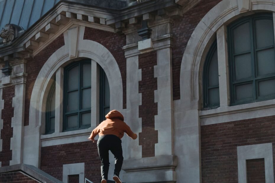 A traceur clearing a brick parapet with hands placed on the edge.
