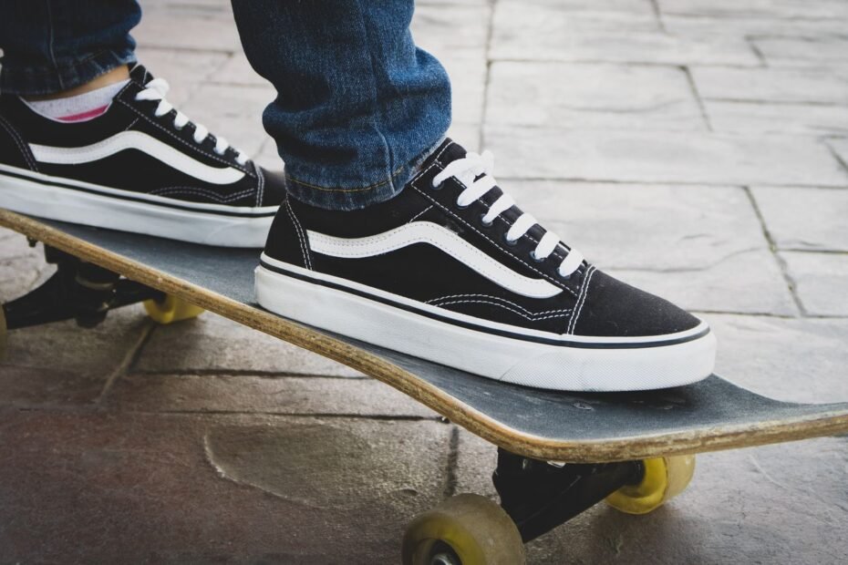 A pair of classic black and white vulcanized skate shoes standing on a skateboard.
