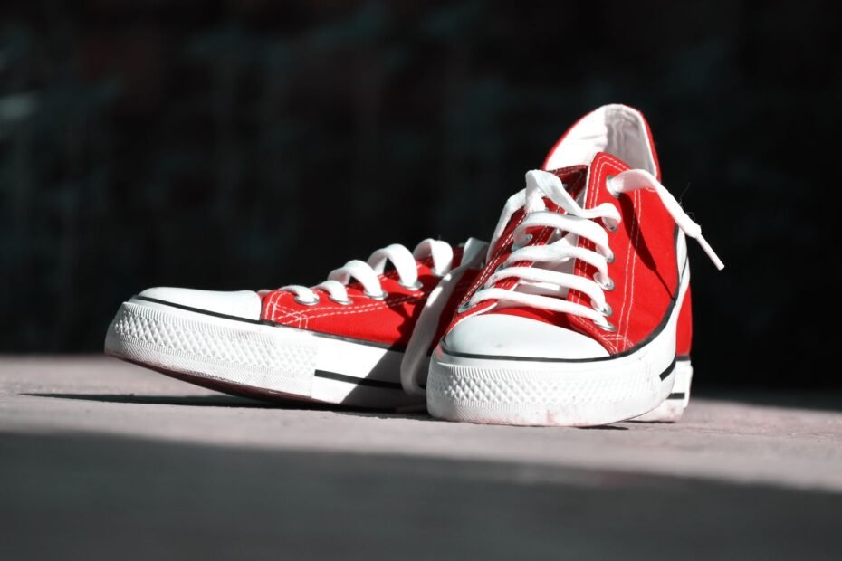 A pair of red canvas low-top trainers with white rubber soles and white laces.