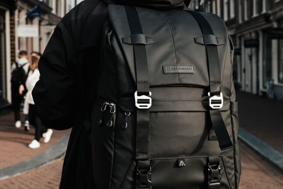 Back view of a man wearing a black backpack with both shoulder straps on a city street.