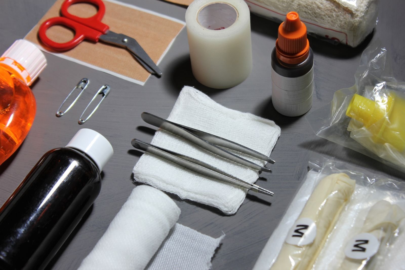 First aid supplies laid out: scissors, tape, gauze, safety pins, bandages and antiseptic bottles.