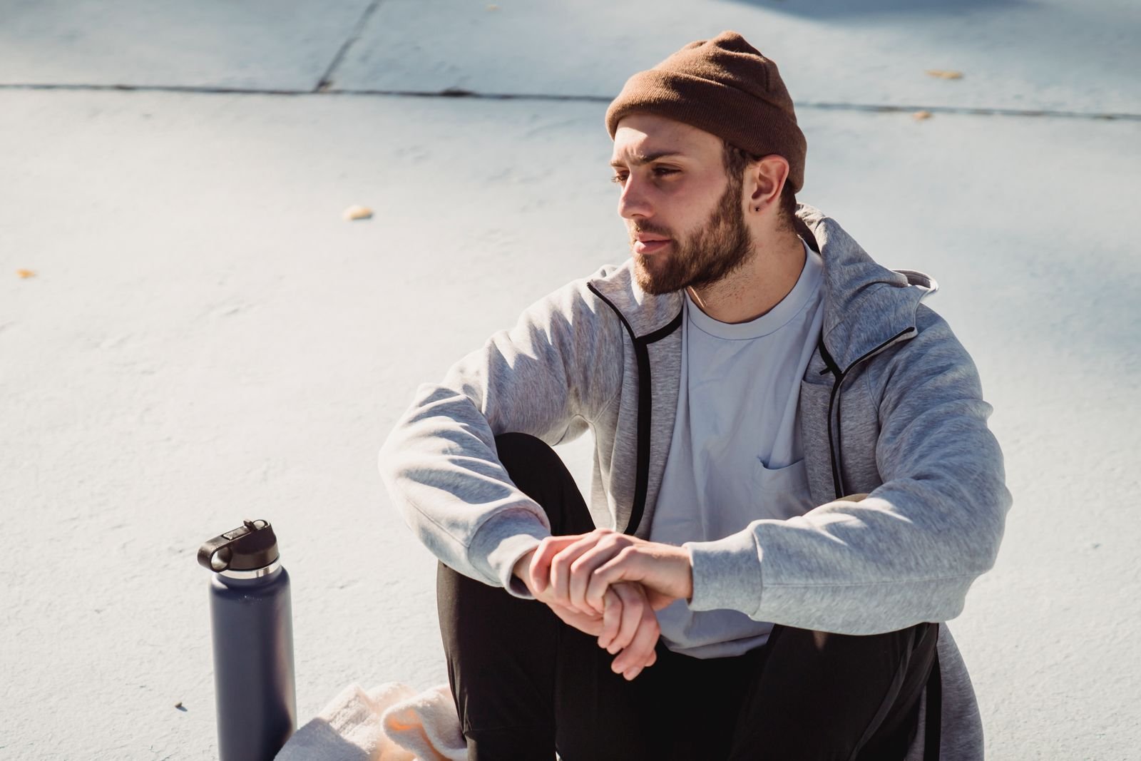 A traceur sitting on the ground next to a water bottle, holding one wrist with the other hand.