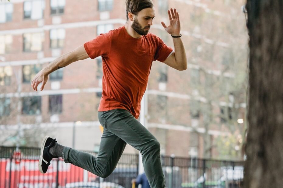 A traceur in a red T-shirt running and jumping between low walls in a city playground.